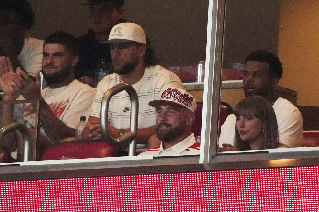 Taylor Swift, front right, sits with fiance Travis Kelce, second from front left, as they watch the first half of an NCAA college football game between Cincinnati and Nebraska, Thursday, Aug. 28, 2025, at Arrowhead Stadium in Kansas City, Mo. (AP Photo/Charlie Riedel)