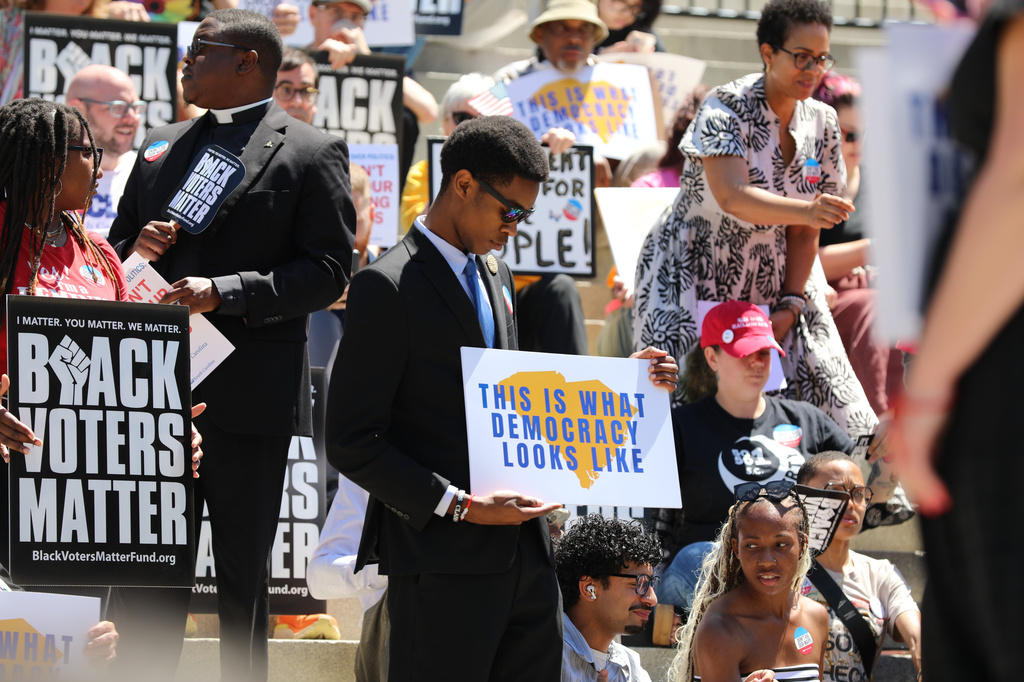 A protestor stands outside the South Carolina Statehouse on Thursday, May 14, 2026, in Columbia, S.C. (AP Photo/Jeffrey Collins)