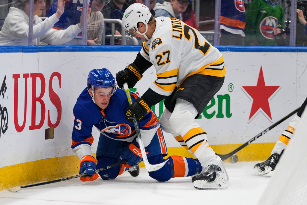 Boston Bruins' Hampus Lindholm (27) checks New York Islanders' Mathew Barzal (13) during the second period of an NHL hockey game Tuesday, Nov. 4, 2025, at UBS Arena in Elmont, N.Y. (AP Photo/Frank Franklin II)