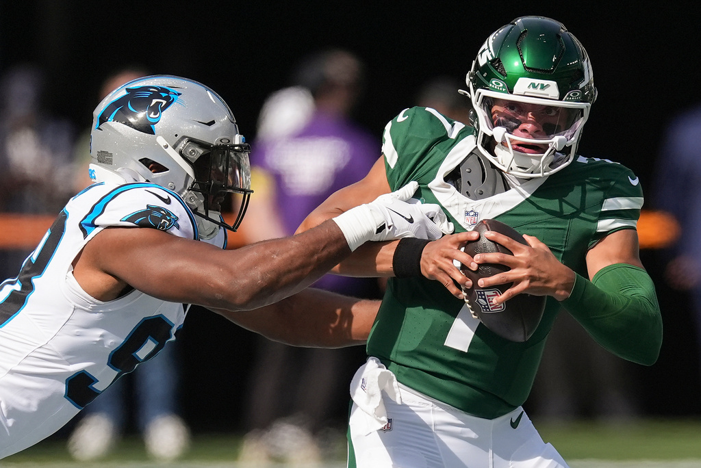 New York Jets quarterback Justin Fields (7) tries to avoid a tackle by Carolina Panthers linebacker D.J. Wonnum (98) during the first quarter of an NFL football game, Sunday, Oct. 19, 2025, in East Rutherford, N.J. (AP Photo/Seth Wenig)