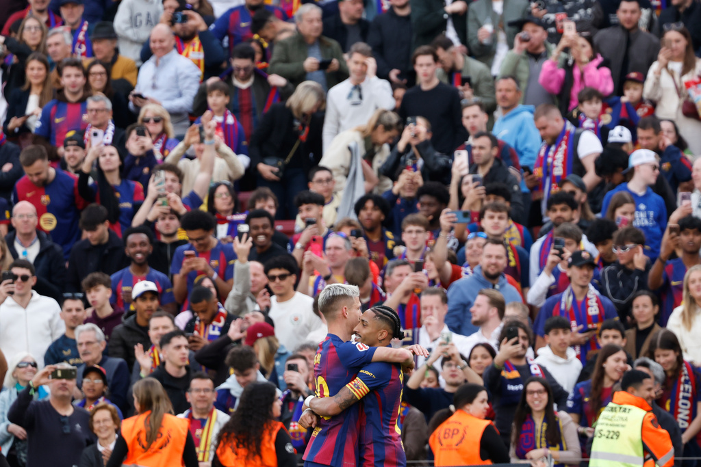 Barcelona's Raphinha, centre right, celebrates with Barcelona's Dani Olmo after scoring his side's fourth goal during the Spanish La Liga soccer match between Barcelona and Sevilla in Barcelona, Spain, Sunday, March 15, 2026. (AP Photo/Joan Monfort)
