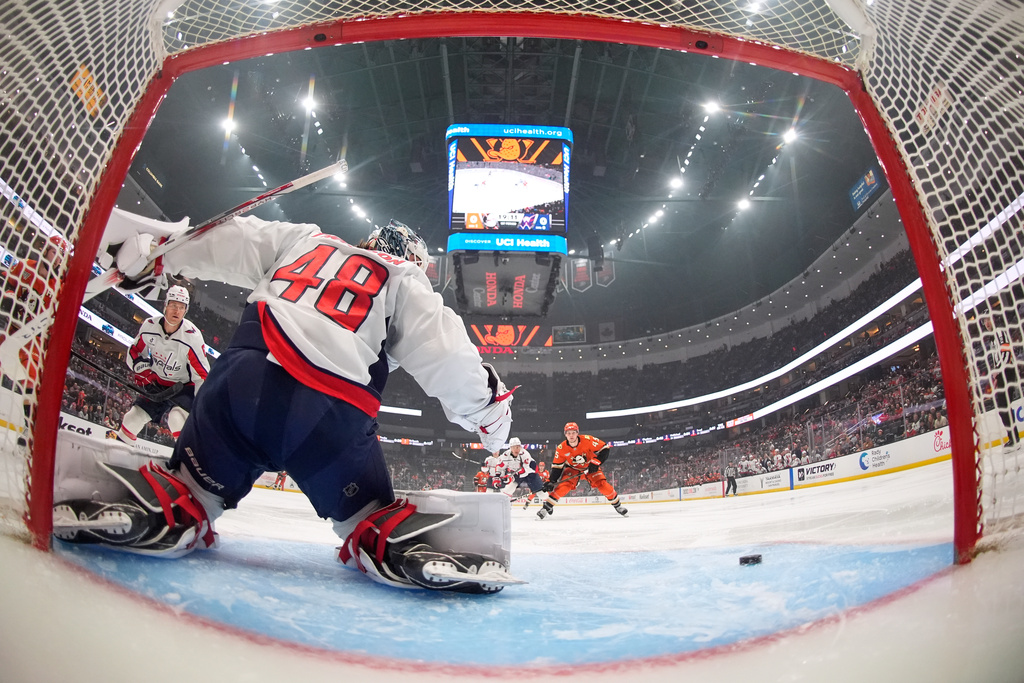 Washington Capitals goaltender Logan Thompson, left, deflects a shot as Anaheim Ducks right wing Beckett Sennecke, right, watches during the first period of an NHL hockey game Friday, Dec. 5, 2025, in Anaheim, Calif. (AP Photo/Mark J. Terrill)