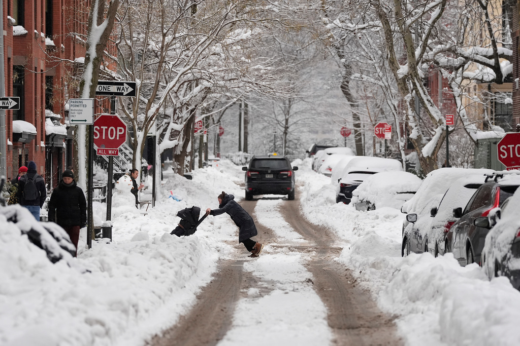 A woman pushes a stroller through plowed snow, Wednesday, Feb. 25, 2026, in the Brooklyn borough of New York. (AP Photo/Yuki Iwamura)