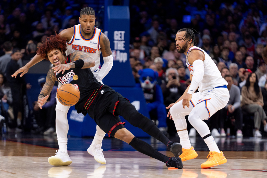 Philadelphia 76ers' Kelly Oubre Jr., left, tries to regain control of the loose ball as New York Knicks' Miles McBride, center, and Jalen Brunson, right, defending during the first half of an NBA basketball game, Saturday, Jan. 24, 2026, in Philadelphia. (AP Photo/Chris Szagola)