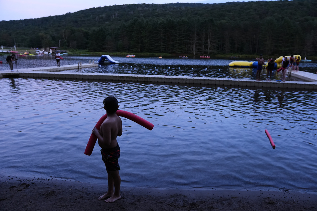 Dylan Aristy Mota, 12, of New York City, who has lupus, stands at the water's edge during a headcount following an evening swim at the Frost Valley YMCA sleepaway camp in Claryville, N.Y., Wednesday, July 30, 2025. The camp partnered with Children's Hospital at Montefiore so kids with autoimmune diseases could attend for the first time. (AP Photo/Matt Rourke)