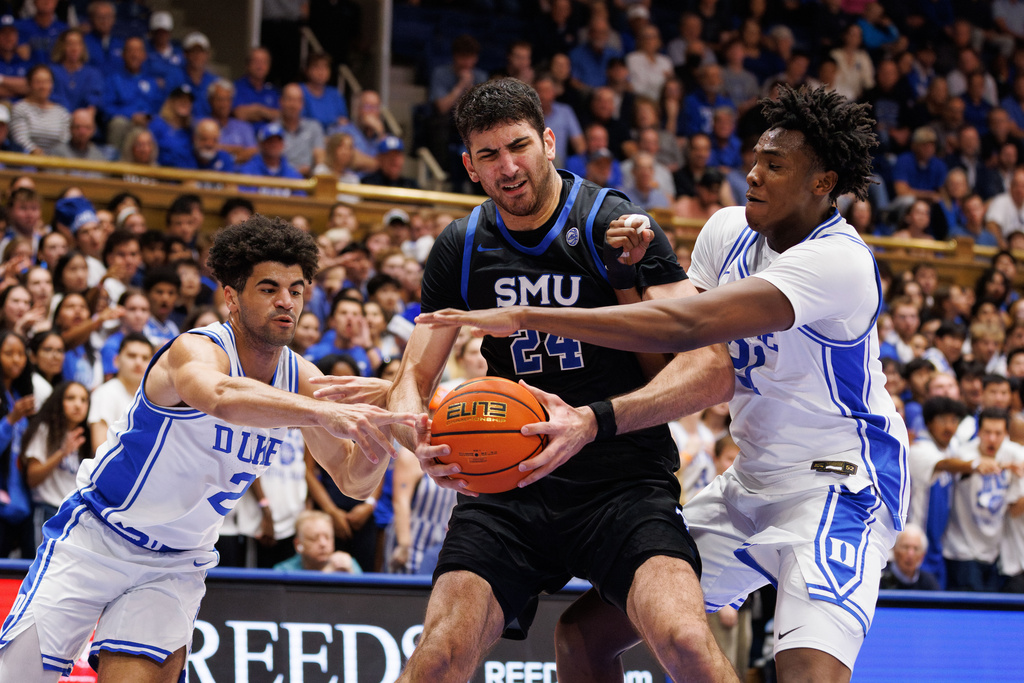 SMU's Samet Yigitoglu (24) handles the ball as Duke's Patrick Ngongba II (21) and Cayden Boozer (2) defend during the first half of an NCAA college basketball game in Durham, N.C., Saturday, Jan. 10, 2026. (AP Photo/Ben McKeown)