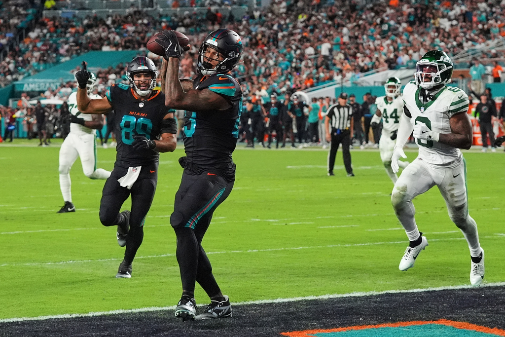Miami Dolphins tight end Darren Waller (83) catches a touchdown pass as Julian Hill (89) celebrates and New York Jets' Andre Cisco, right, defends in the second half of an NFL football game, Monday, Sept. 29, 2025, in Miami Gardens, Fla. (AP Photo/Marta Lavandier)
