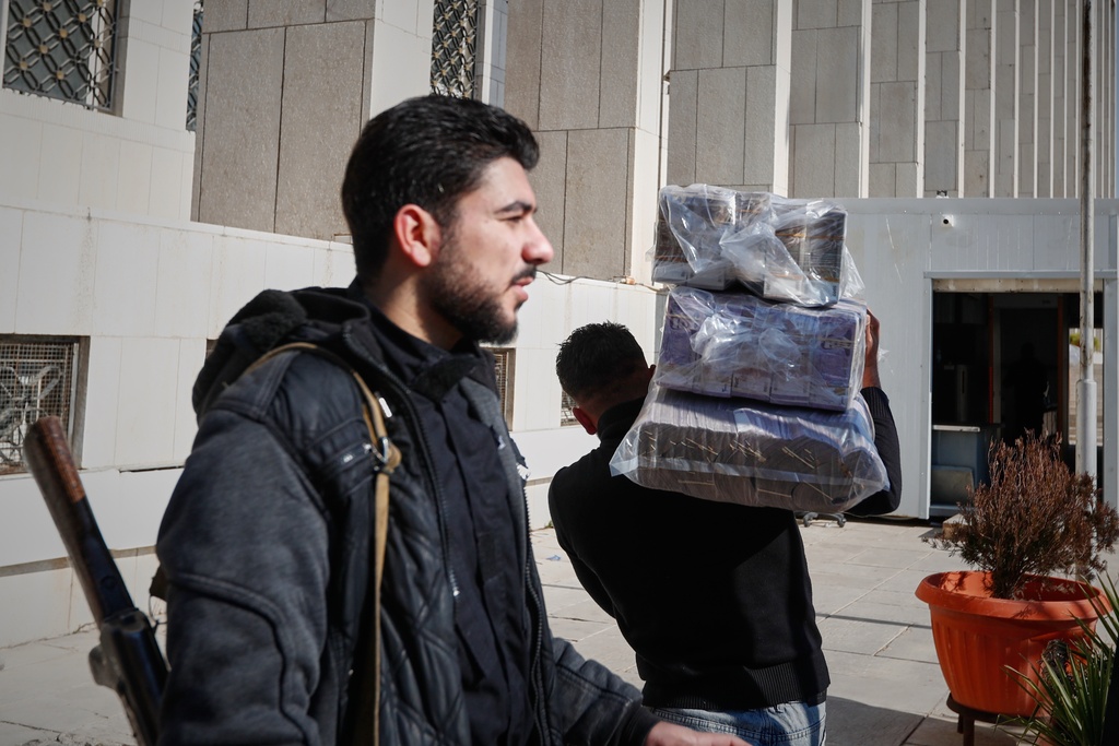 A man carries bundles of old currency bills to deposit at the Syrian Central Bank office after authorities announced Saturday that the exchange of old Syrian pounds for new banknotes has officially begun in Damascus, Syria, Saturday, Jan. 3, 2026. (AP Photo/Omar Sanadiki)