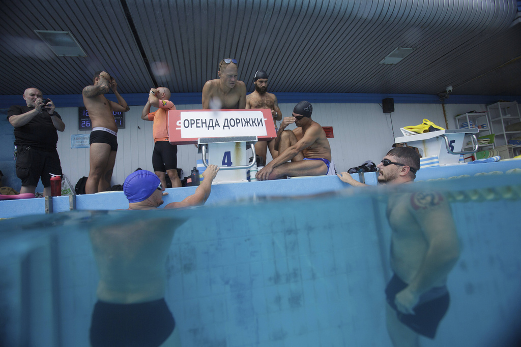 Coach Roman Korol, center, instructs Ukrainian war veteran Oleksandr Dashko, right, at a pool in Kyiv, Ukraine, Tuesday, Aug. 12, 2025, during a training session for the upcoming 6.5km swimming race across the Bosporus Strait, (AP Photo/Evgeniy Maloletka)