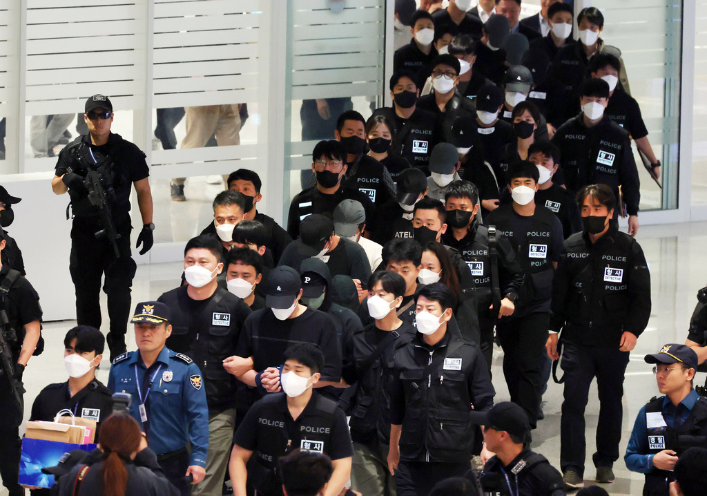 South Koreans, wearing caps, allegedly involved in online scams in Cambodia arrive at the Incheon International Airport, in Incheon, Saturday, Oct. 18, 2025. (Yonhap via AP)