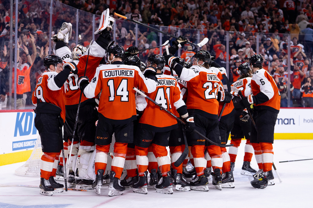 The Philadelphia Flyers gather around the net of goalie Dan Vladar, second from left, to celebrate a win and clinching a playoff berth after an NHL hockey game against the Carolina Hurricanes, Monday, April 13, 2026, in Philadelphia. (AP Photo/Chris Szagola)