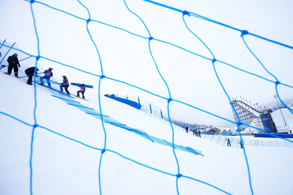 Workers set up fencing along the slopestyle course before a training session at the 2026 Winter Olympics, in Livigno, Italy, Wednesday, Feb. 4, 2026. (AP Photo/Gregory Bull)