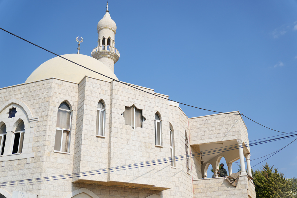 A soldier stands guard while Israeli army inspectors tour a mosque that was torched and defaced by Israeli settlers overnight, in the West Bank town of Deir Istiya Thursday, Nov. 13, 2025. (AP Photo/Nasser Nasser)