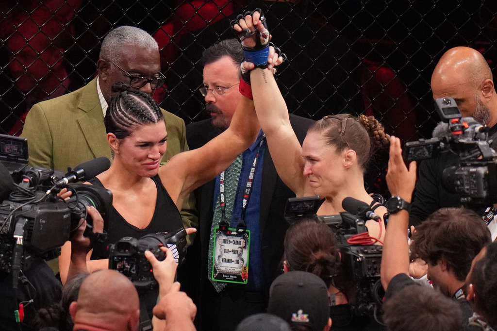 Gina Carano, of the United States, left, lifts the arm of Ronda Rousey, of the United States, after Rousey defeated Carano in their featherweight mixed martial arts fight Saturday, May 16, 2026, in Inglewood, Calif. (AP Photo/Jae C. Hong )