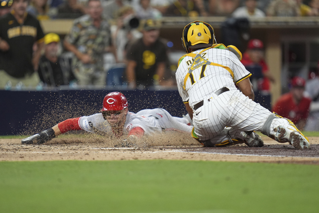 The helmet of Cincinnati Reds' TJ Friedl, left, slides into home, scoring from second base off an RBI single by Elly De La Cruz as San Diego Padres catcher Elias Diaz is late with the tag during the eighth inning of a baseball game Wednesday, Sept. 10, 2025, in San Diego. (AP Photo/Gregory Bull)