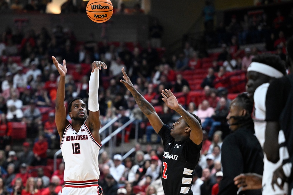 Texas Tech forward Donovan Atwell (12) shoots the ball while Cincinnati guard Jizzle James (2) defends during the first half of an NCAA college basketball game Tuesday, Feb. 24, 2026, in Lubbock, Texas. (AP Photo/Justin Rex)