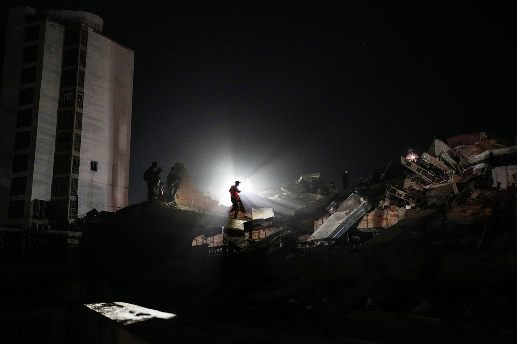 Residents and rescue workers search through the rubble two days after an earthquake struck in La Guaira, Venezuela, Friday, June 26, 2026. (AP Photo/Matias Delacroix)