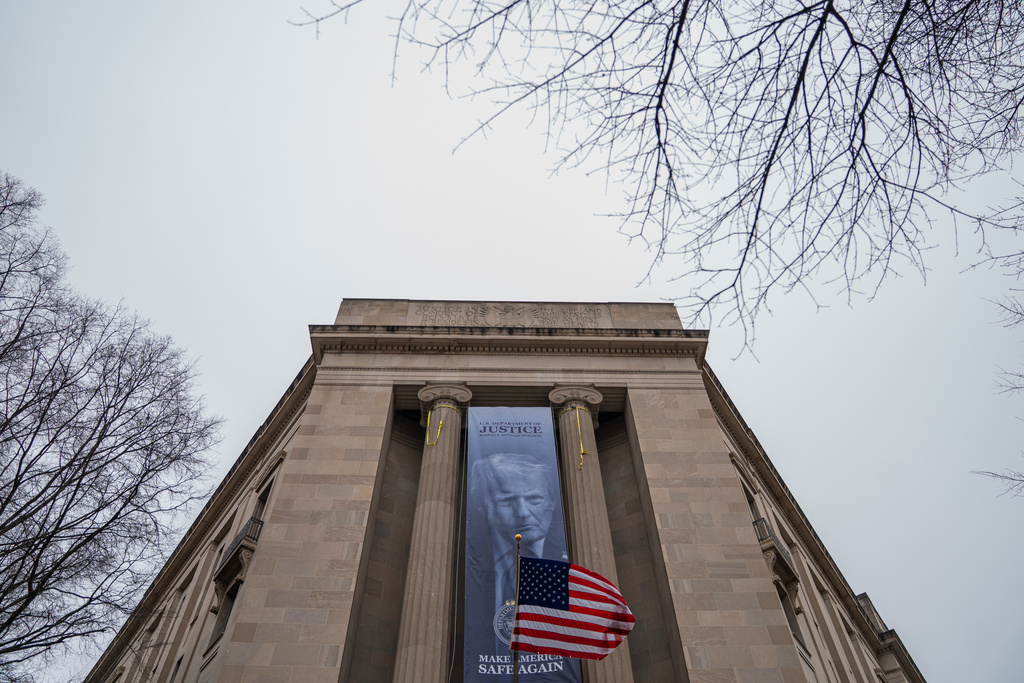 A banner showing President Donald Trump is hung from the Department of Justice, Thursday, Feb. 19, 2026, in Washington. (AP Photo/Allison Robbert)