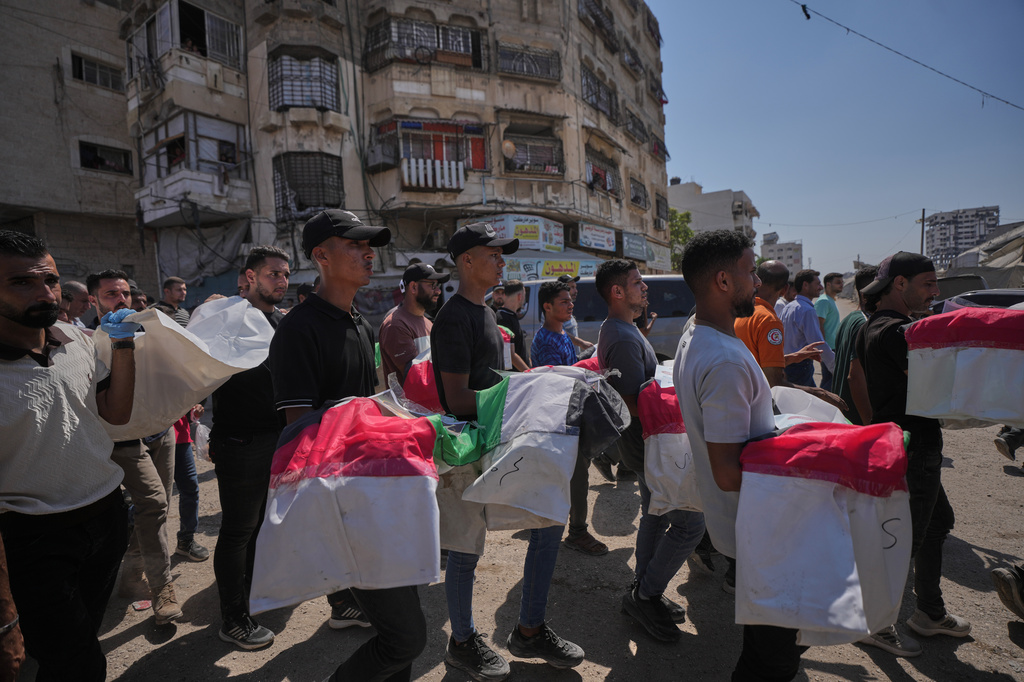Mourners carry the flag-draped bodies of Palestinians killed in Israeli strikes during the war with Hamas, whose remains were recently recovered from the rubble, in Gaza City, Thursday, Aug. 20, 2026. (AP Photo/Jehad Alshrafi)
