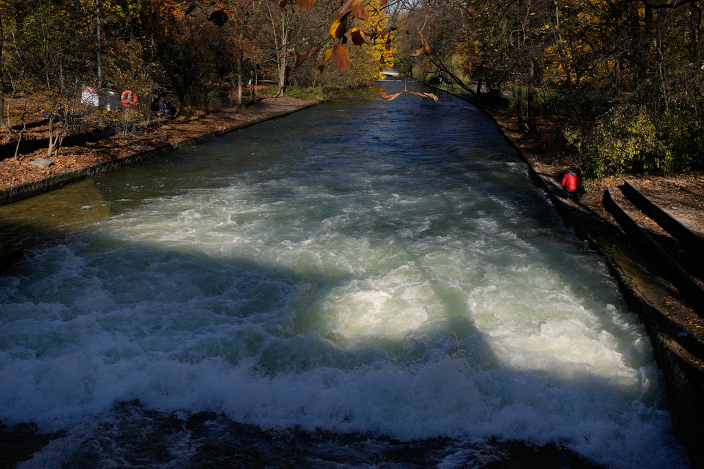 A man films at the Eisbach, where the famous wave usually forms, in Munich, Germany, Wednesday, Nov. 5, 2025. (AP Photo/Matthias Schrader)