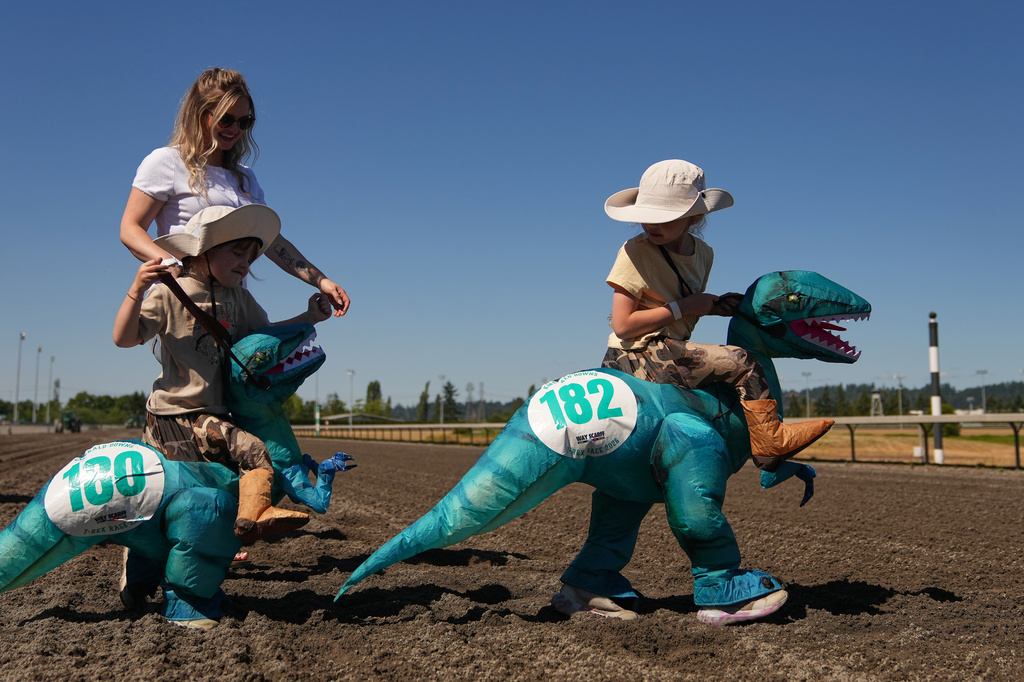 Young racers walk on the track to the starting gate for a kids' heat during the T-Rex World Championship Races at Emerald Downs, Sunday, July 12, 2026, in Auburn, Wash. (AP Photo/Lindsey Wasson)