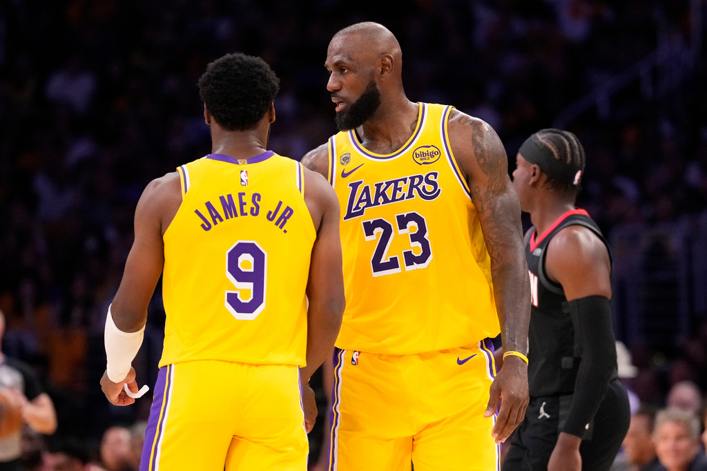Los Angeles Lakers forward LeBron James, right, talks to his son guard Bronny James during the first half in Game 1 of a first-round NBA playoffs basketball series against the Houston Rockets, Saturday, April 18, 2026, in Los Angeles. (AP Photo/Mark J. Terrill)