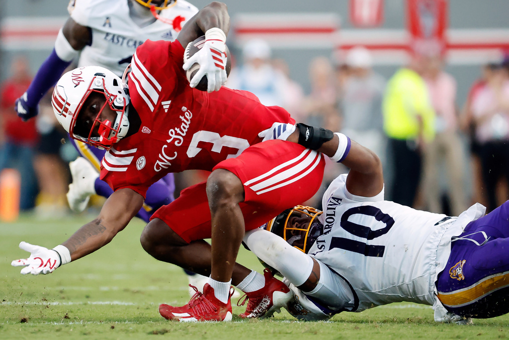 North Carolina State's Hollywood Smothers (3) struggles in the grasp of East Carolina's Dameon Wilson (10) during the first half of an NCAA college football game in Raleigh, N.C., Thursday, Aug. 28, 2025. (AP Photo/Karl DeBlaker)