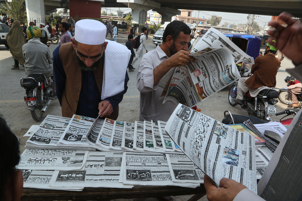 People read morning newspapers covering headline story about overnight cross border fighting between Pakistan and Afghan forces, at a stall in Peshawar, Pakistan, Friday, Feb. 27, 2026. (AP Photo/Muhammad Sajjad)