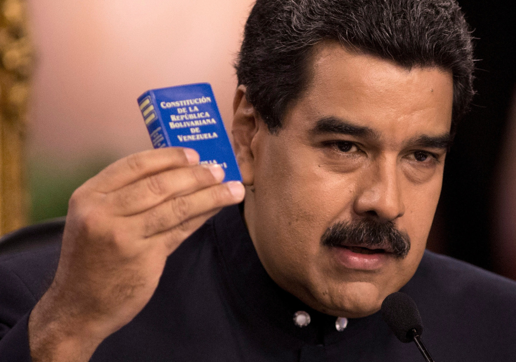 FILE - Venezuela's President Nicolas Maduro holds a copy of the constitution, as he speaks during a news conference in Caracas, Venezuela, Aug. 22, 2017. (AP Photo/Ariana Cubillos, File)