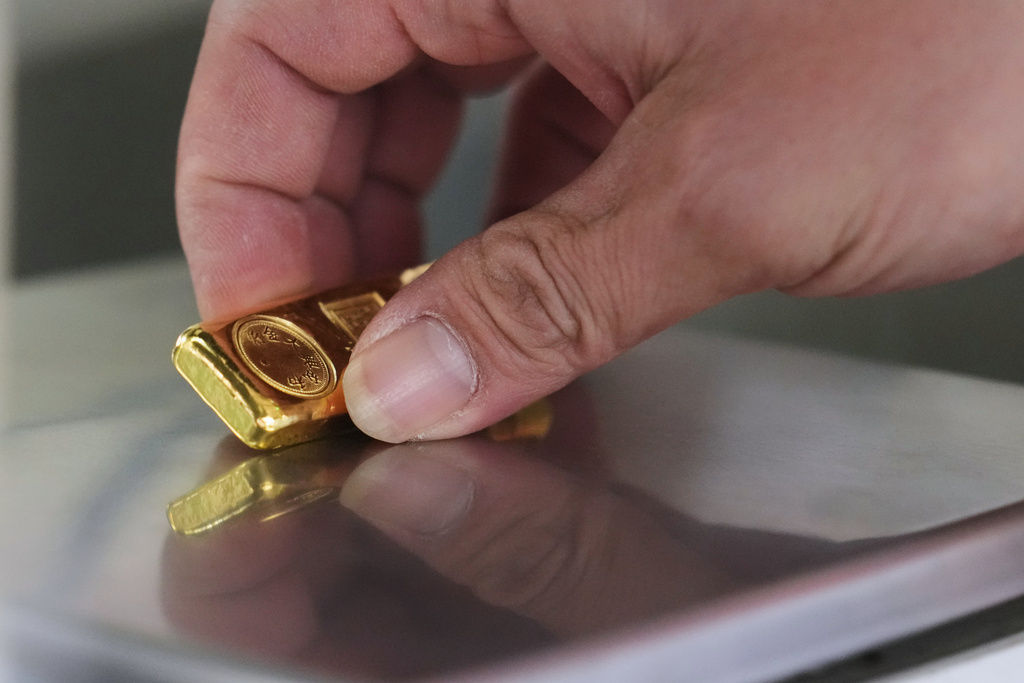 A gold jeweler weighs a gold bar for sale in Bangkok, Thailand, Thursday, Jan. 29, 2026. (AP Photo/Sakchai Lalit)