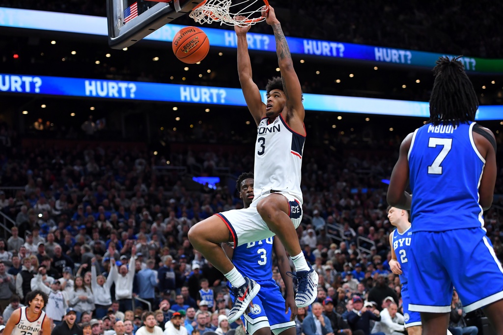 UConn forward Jaylin Stewart (3) hangs from the rim after dunking in front of BYU forward AJ Dybantsa (3) and forward Khadim Mboup (7) in the second half of an NCAA college basketball game, Saturday, Nov. 15, 2025, in Boston. (AP Photo/Steven Senne)