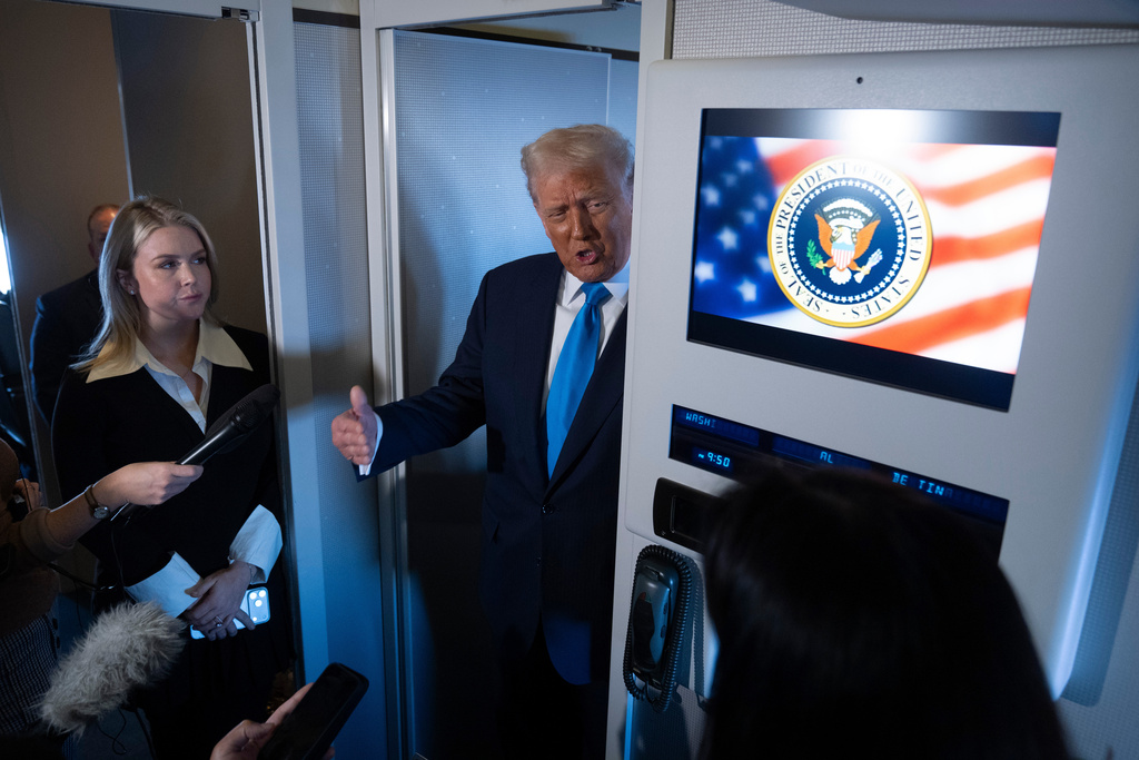 President Donald Trump speaks to reporters as Press Secretary Karoline Leavitt, left, listens, aboard Air Force One as he travels from Tokyo, Japan, to South Korea, Wednesday, Oct. 29, 2025. (AP Photo/Mark Schiefelbein)