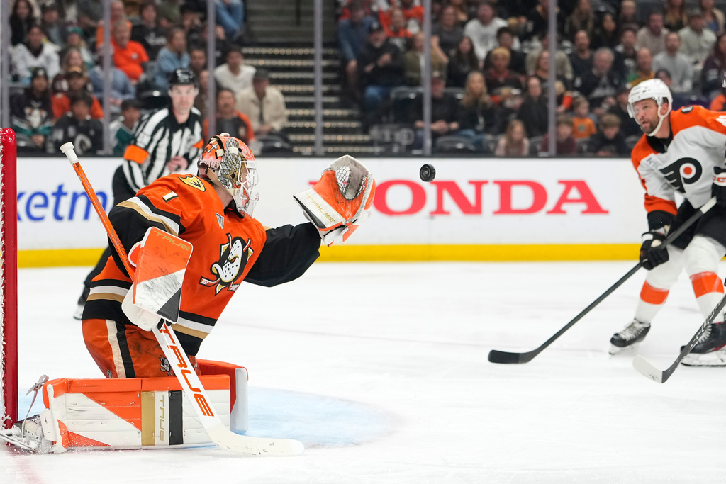 Anaheim Ducks goaltender Lukas Dostal, left, stops a shot as Philadelphia Flyers center Luke Glendening watches during the second period of an NHL hockey game Wednesday, March 18, 2026, in Anaheim, Calif. (AP Photo/Mark J. Terrill)