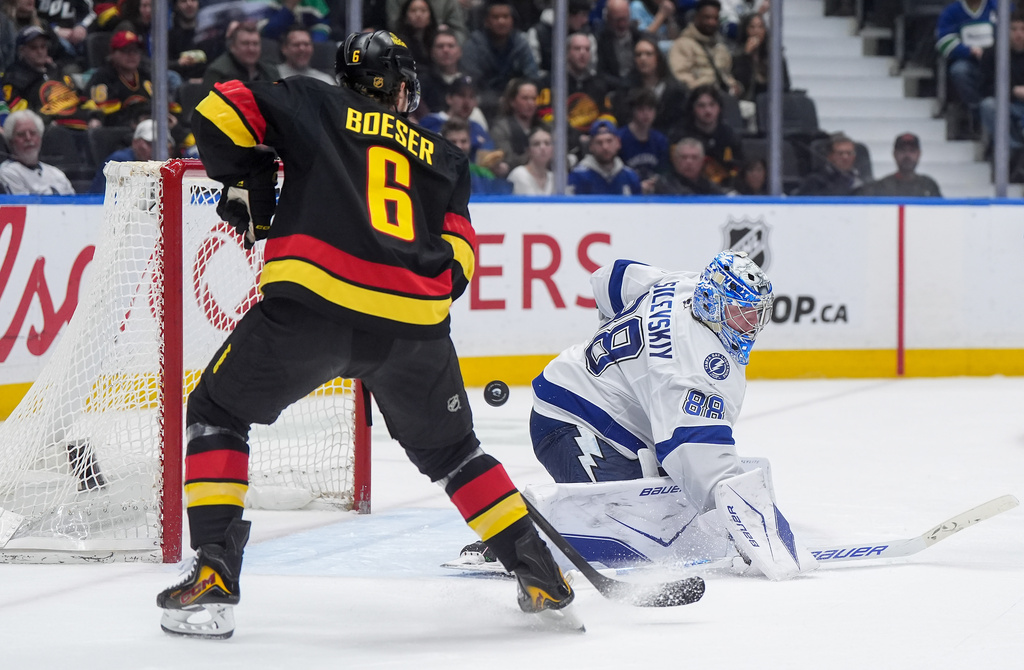 Tampa Bay Lightning goalie Andrei Vasilevskiy (88) makes a save as the puck bounces past Vancouver Canucks' Brock Boeser (6) and wide of the net during the third period of an NHL hockey game in Vancouver, British Columbia, Thursday, March 19, 2026. (Darryl Dyck/The Canadian Press via AP)