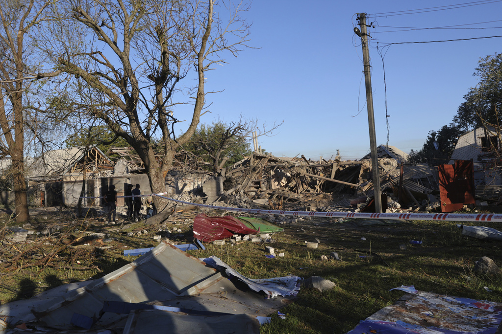 People stand near a building destroyed during a Russian strike in Zaporizhzhia, Ukraine, Monday, Sept. 22, 2025. (AP Photo/Kateryna Klochko)
