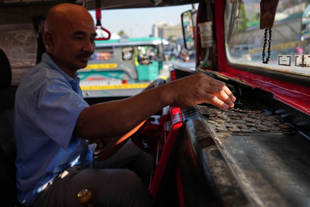Jeepney driver Edilberto Globio Jr. counts coins as he parks his vehicle at a terminal in Pasay city, Philippines as the rise in oil prices continues to affect their livelihood on Monday, March 23, 2026. (AP Photo/Aaron Favila)