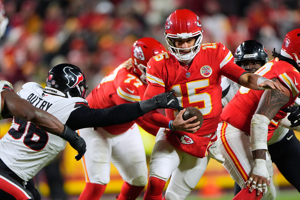 Kansas City Chiefs quarterback Patrick Mahomes (15) scrambles as Houston Texans defensive end Denico Autry, left, defends during the first half of an NFL football game Sunday, Dec. 7, 2025, in Kansas City, Mo. (AP Photo/Charlie Riedel)