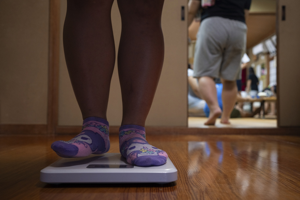 A wrestler weighs herself on a scale during a sumo camp in Tottori Johoku High School in Tottori, Japan, on July 28, 2025. (AP Photo/Louise Delmotte)