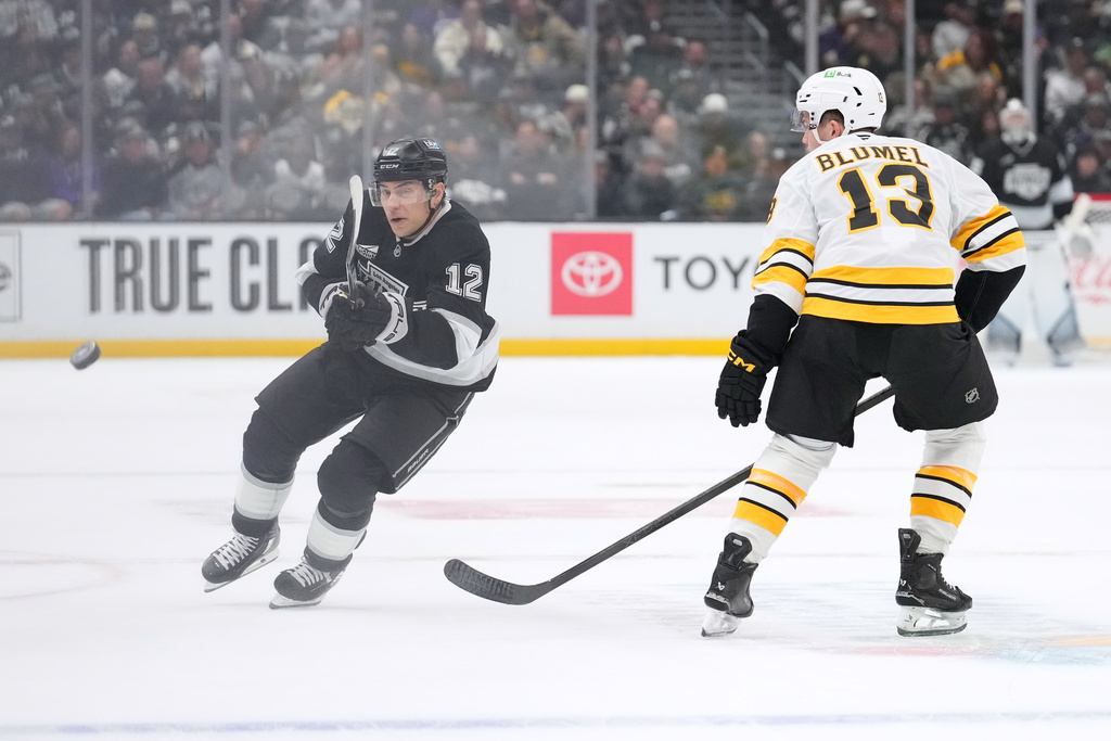 Los Angeles Kings left wing Trevor Moore, left, passes the puck while under pressure from Boston Bruins right wing Matej Blumel during the second period of an NHL hockey game Friday, Nov. 21, 2025, in Los Angeles. (AP Photo/Mark J. Terrill)