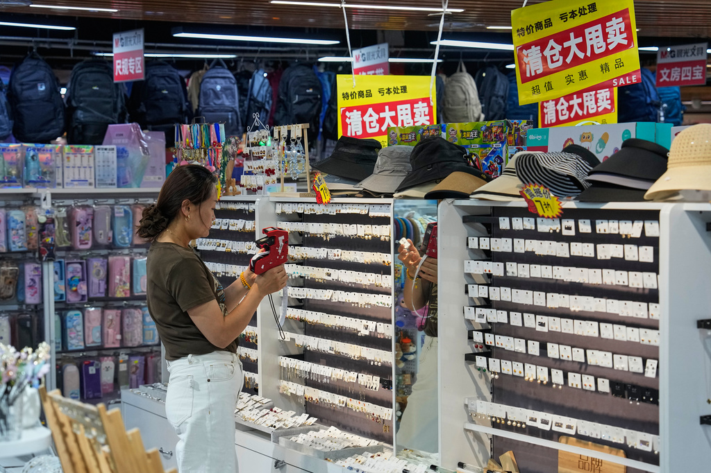 A vendor puts price tag on the ear rings for sale at her store in Beijing, China on Wednesday, July 15, 2026. (AP Photo/Andy Wong)