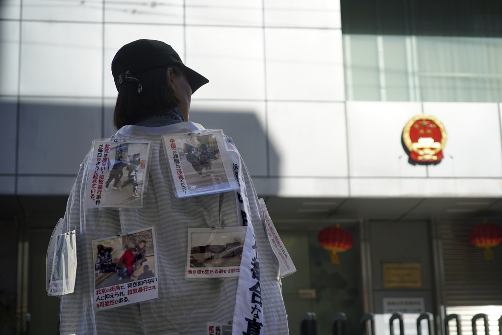 Yang Caiying, who is living in exile in Japan, wears signs protesting state repression of her family outside the Chinese consulate in Nagoya, Japan, Friday, May 17, 2024. (AP Photo/Dake Kang)