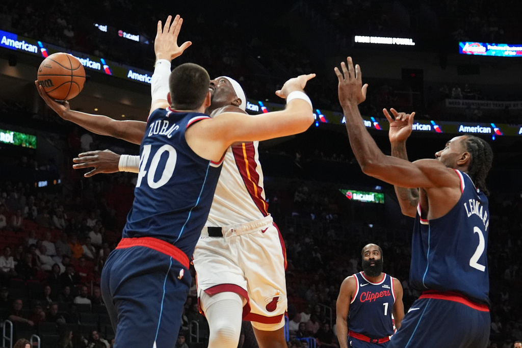 Miami Heat center Bam Adebayo, center, goes to the basket as Los Angeles Clippers center Ivica Zubac (40) and forward Kawhi Leonard (2) defend during the first half of an NBA basketball game, Monday, Dec. 1, 2025, in Miami. (AP Photo/Lynne Sladky)