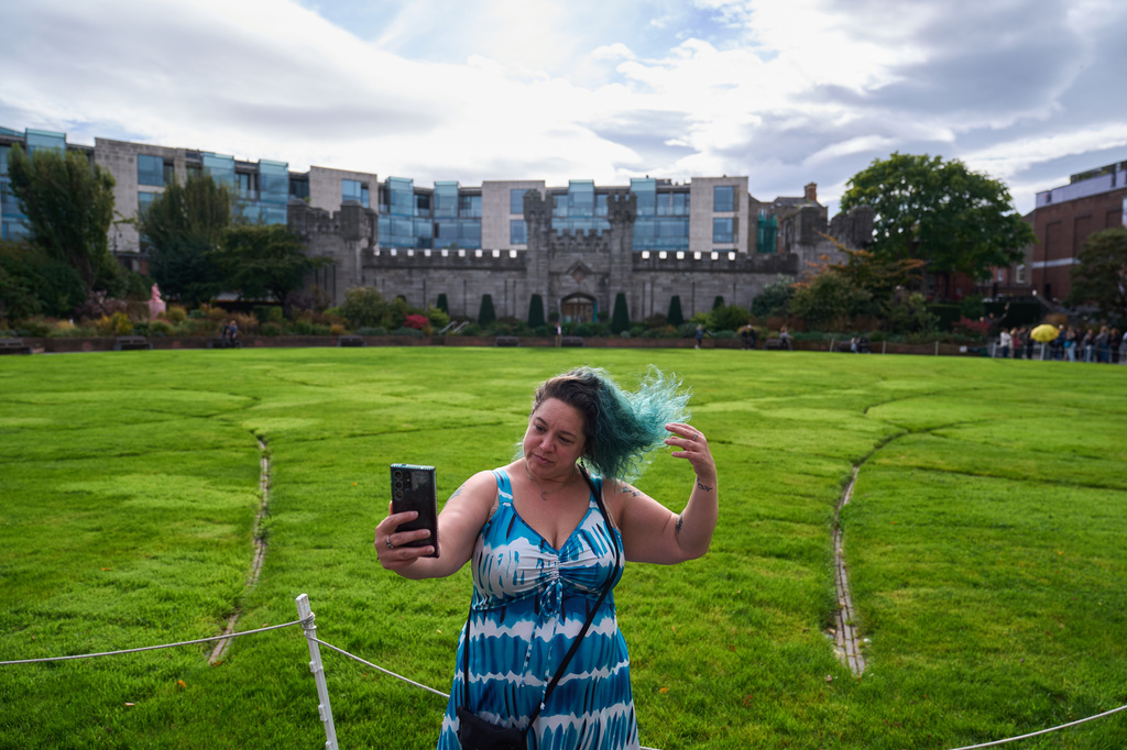 Jean Booth, who is traveling around Europe to get away after being targeted in a romance scam that lasted eight months, takes a selfie while visiting the gardens of Dublin Castle, Oct. 1, 2025, in Dublin. (AP Photo/David Goldman)