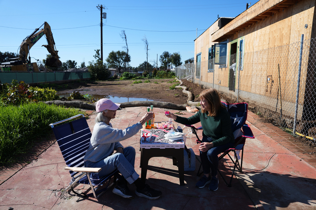 Gail Kass, right, shares a lunch with her neighbor Sandy Oshinomi as homes are rebuilt around them on the one-year anniversary of the Palisades Fire in the Pacific Palisades neighborhood of Los Angeles Wednesday, Jan. 7, 2026. (AP Photo/Jae C. Hong)