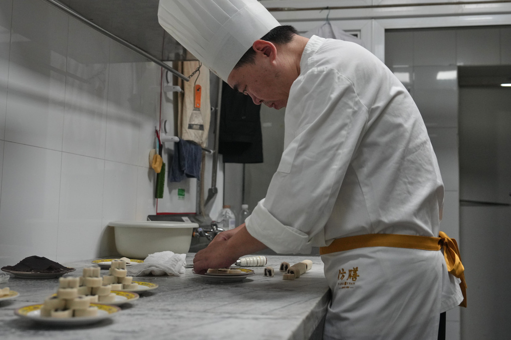Chef Zhou Tong makes the minced pork pancake at Fangshan Restaurant inside Beihai Park in Beijing on July 23, 2026. (AP Photo/Andy Wong)