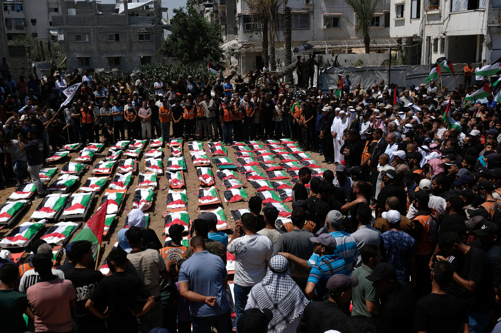 Mourners gather around the flag-draped bodies of members of the Hassayna and Abu Sharia families, killed in an Israeli strike in 2023 and recently recovered from the rubble, during their funeral in Gaza City, Tuesday, Aug. 4, 2026. (AP Photo/Jehad Alshrafi)