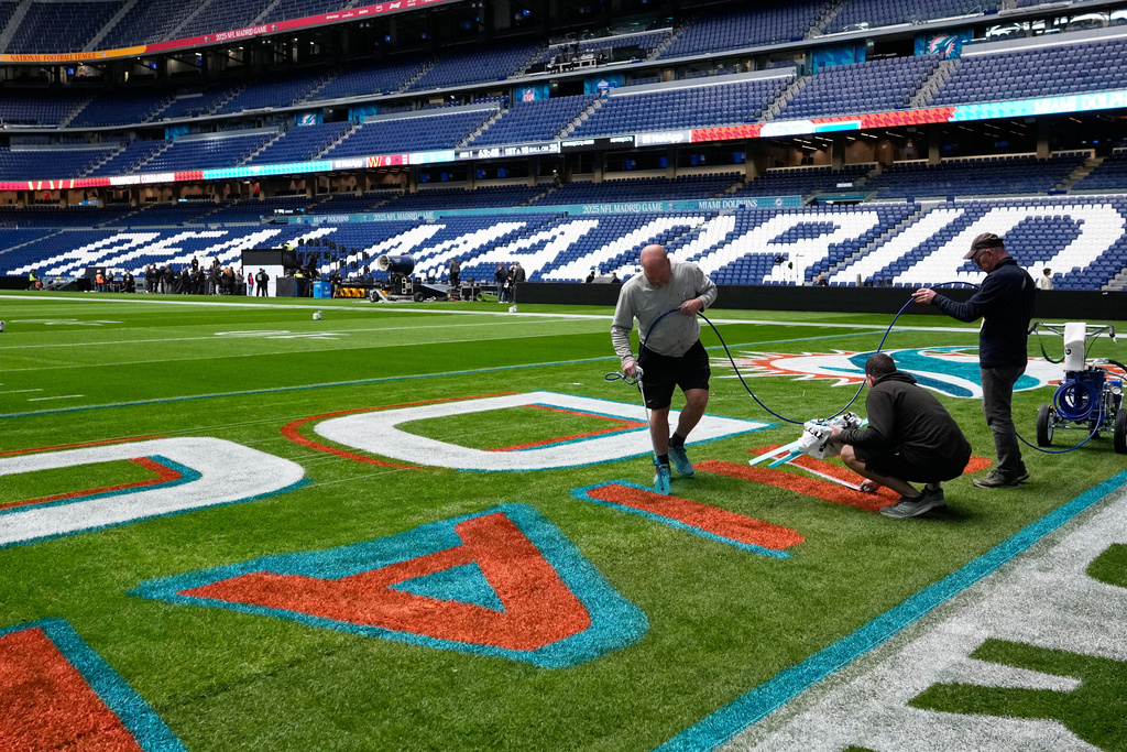 Workers prepare the field at the Santiago Bernabeu stadium ahead of an NFL game between the Miami Dolphins and Washington Commanders in Madrid, Spain, Friday, Nov. 14, 2025. (AP Photo/Steve Luciano)