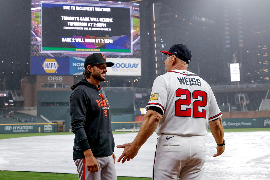 San Francisco Giants manager Tony Vitello, left, speaks with Atlanta Braves manager Walt Weiss after the game was suspended due to weather in the second inning of a baseball game, Tuesday, June 16, 2026, in Atlanta. (AP Photo/Erik S. Lesser)
