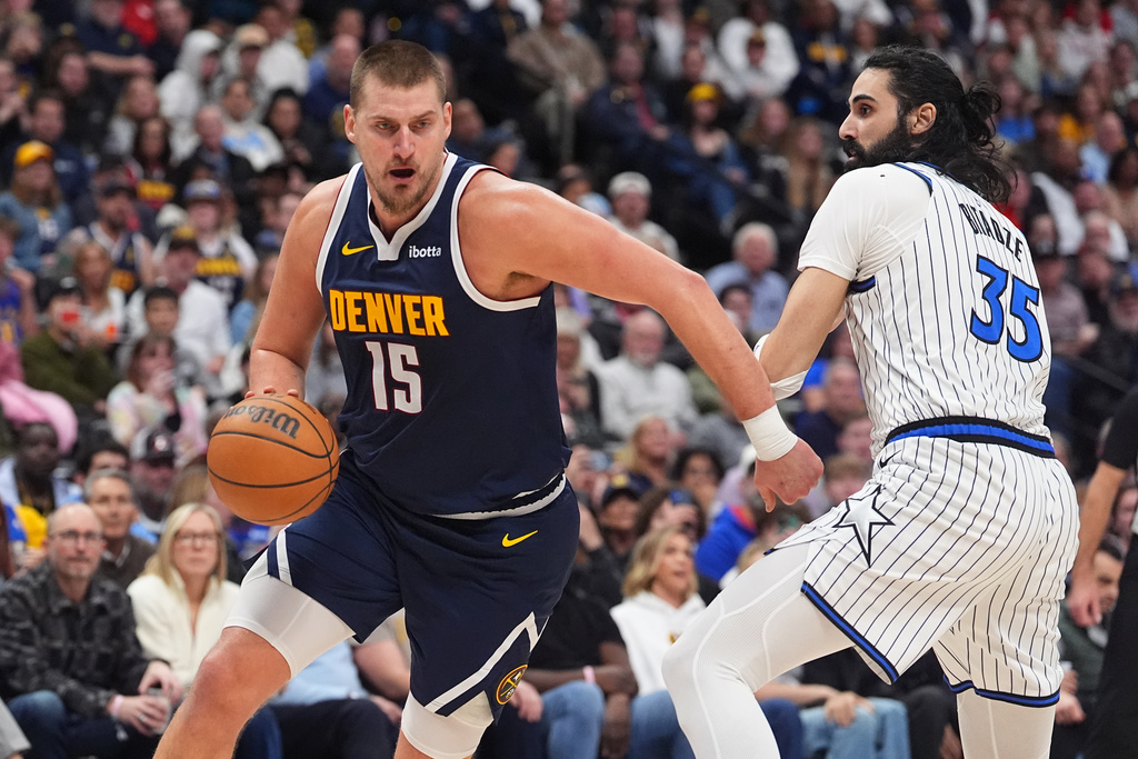 Denver Nuggets center Nikola Jokić drives (15) past Orlando Magic center Goga Bitadze (35) in the second half of an NBA basketball game Thursday, Dec. 18, 2025, in Denver. (AP Photo/David Zalubowski)