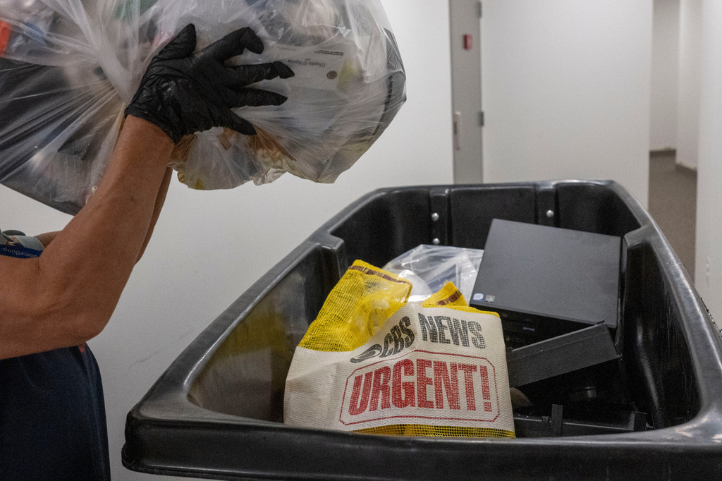 A cleaning person throws a bag of trash in a dumpster as members of the media pack up their belongings in the press area of the Pentagon, Wednesday, Oct. 15, 2025 in Washington. (AP Photo/Kevin Wolf)